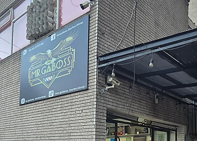 Esquina de Av. Cuatro con el letrero negro de Mr. Gaboss y su águila dorada sobre el muro de ladrillo gris
