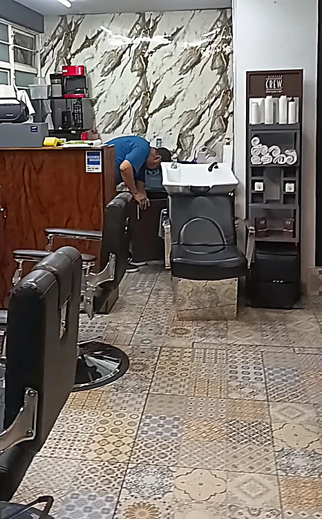 Interior de Mr. Gaboss: muro de mármol blanco con vetas café junto al lavacabezas, sillones de barbero negros y piso de mosaico de pasta